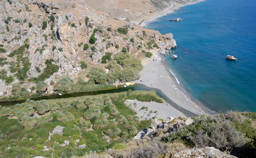 Weiter geht´s: Der Palmenstrand von Preveli befindet sich an einer kleinen Bucht des Libyschen Meeres, 23 Kilometer südlich der an der Nordküste Kretas liegenden Präfekturhauptstadt Rethymno und 8,5 Kilometer südöstlich des Gemeindehauptortes Plakias der Gemeinde Finikas an der Bucht von Plakias. Er bildet den südlichen Endpunkt der etwa zwei Kilometer langen Schlucht von Preveli, die der Megalopotamos über Jahrmillionen bis zu seiner Mündung am Palmenstrand in den Fels geschnitten hat. Nördlich dieser Schlucht schließt eine hügelige Ebene an, bevor ab vier Kilometer Entfernung vom Meer das Kouroupa-Massiv bis auf eine Höhe von 983 Metern ansteigt, nur unterbrochen von der Kourtaliotiko- und der Frati-Schlucht, aus denen der Megalopotamos und sein östlicher Zufluss, der Bourtzoukos oder Kissamos, Richtung Südküste streben.