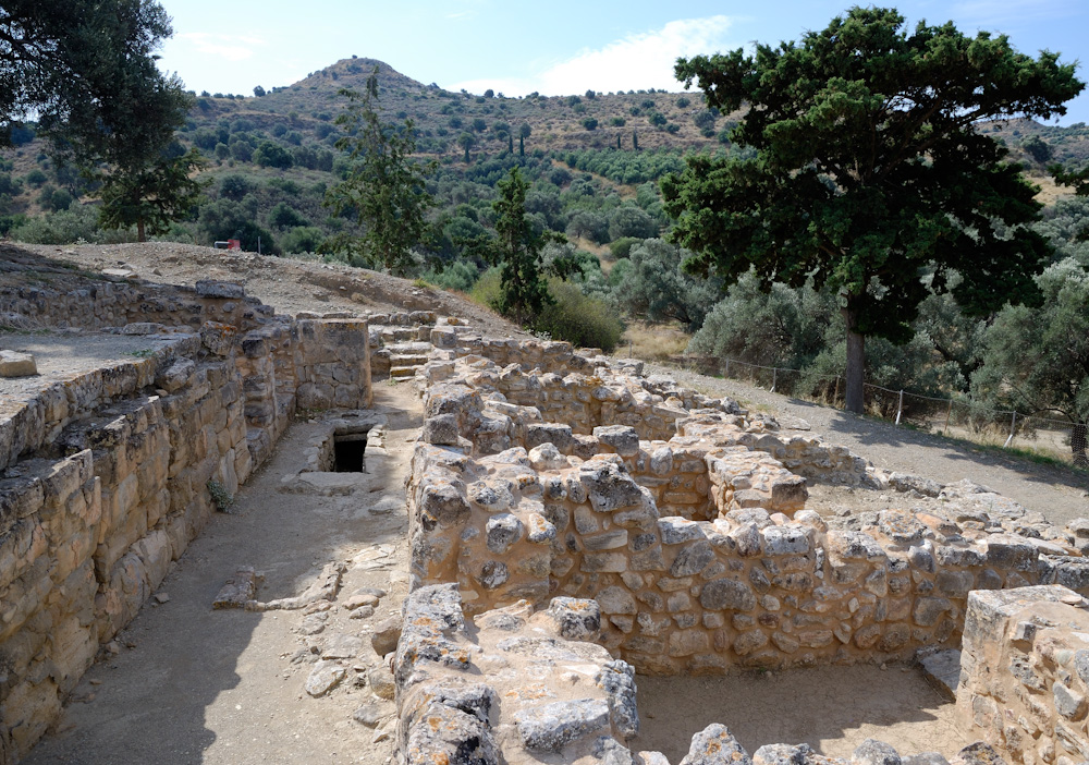 Agia Triada, Der kleine Palast wurde um 1450 v. Chr. zerstört. Danach entstand auf seinen Ruinen ein mykenischer Megaron-Bau. Nördlich unterhalb der Anlage schloss sich in der Nachpalastzeit eine Bebauung aus Wohnungen und Läden (auch als Magazine bezeichnet) an, die sich um eine Agora gruppierten. Sie stellt das einzige bekannte Beispiel eines „minoischen Marktdorfes“ dar. Es wird vermutet, dass sich hier Handwerker und Kaufleute angesiedelt hatten, die intensive Handelsbeziehungen nach Nordafrika pflegten. Am Golf von Messara an der Südküste Kretas befand sich in nur sechs Kilometern Entfernung südwestlich von Agia Triada die minoische Hafensiedlung Komos.